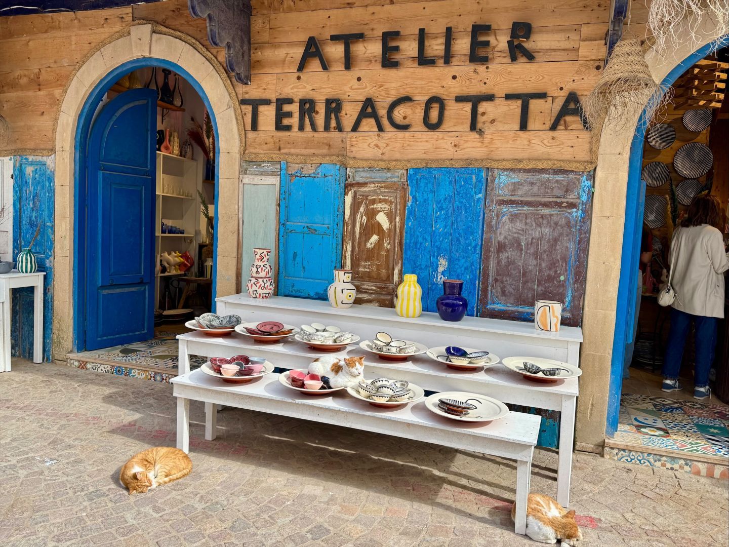 Fron of a potter atelier in Morocco with a cat sleeping on a plate.
